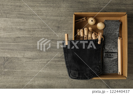 Pieces of denim fabric and box on wooden background, space for text 122440437