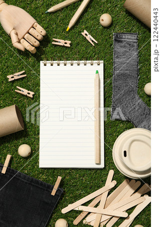Materials for upcycling, wooden hand and notepad on green background, top view 122440443