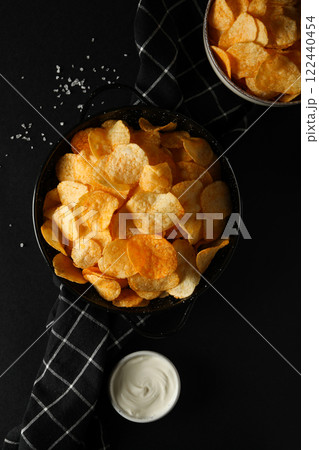 Potato chips in a black bowl on a dark background Potato chips in a black bowl on a dark background 122440454