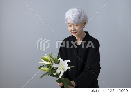 喪服を着て百合の花を持っているシニア女性 喪服を着て百合の花を持っているシニア女性 122441000
