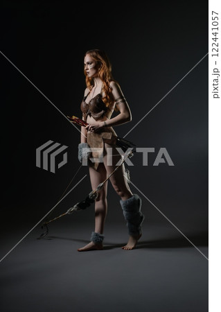 A warrior stands confidently with a bow and arrows in a dark studio setting 122441057