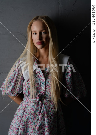 A young woman in a floral dress poses elegantly against a dark background A young woman in a floral dress poses elegantly against a dark background 122441064