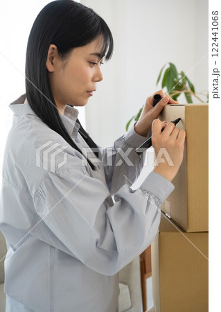 段ボール箱に中に入っているものを書き込む女性 122441068