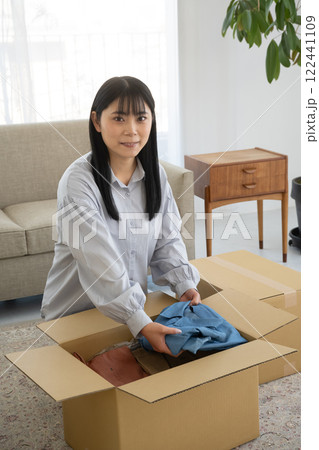 段ボール箱に衣類を詰める女性 122441109