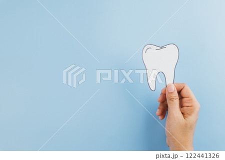 Dentist Day, a woman hands carefully hold a tooth paper cutout 122441326