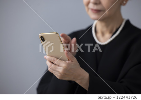 喪服　スマホを見ているシニア女性の手元 122441726