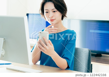 オフィスでスマホを操作する若い女性 122442108