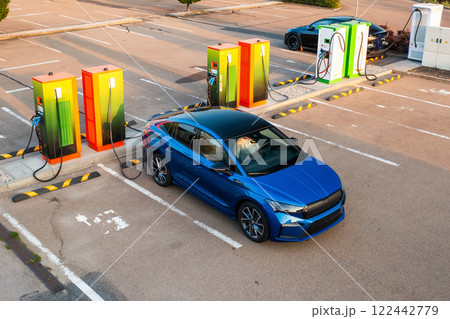 Modern vehicle receives electricity at public charging point. Parking lot equipped with plugs and connectors for quick replenishing of energy 122442779