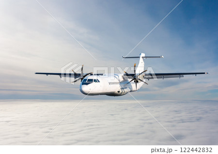 White passenger turboprop aircraft flies in the air above the clouds 122442832