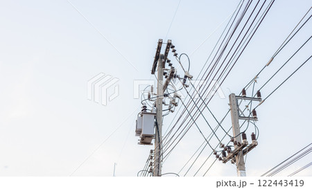 Electrical energy transfer distribution on concrete pole against white sky background, AC high-voltage power transformer, A low angle shot of a power transformer and electrical wires on a metal pole Electrical energy transfer distribution on concrete pole against white sky background, AC high-voltage power transformer, A low angle shot of a power transformer and electrical wires on a metal pole 122443419