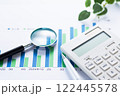 会社の業績グラフと電卓とルーペ 122445578