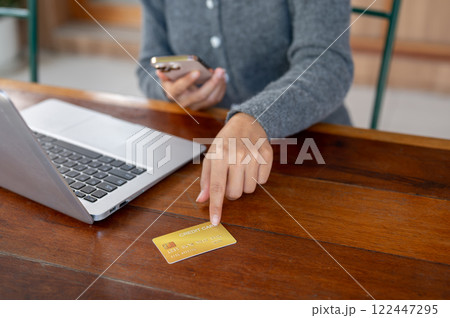 A close-up of a woman pointing at a credit card on a table, shopping online, cashless lifestyles. 122447295