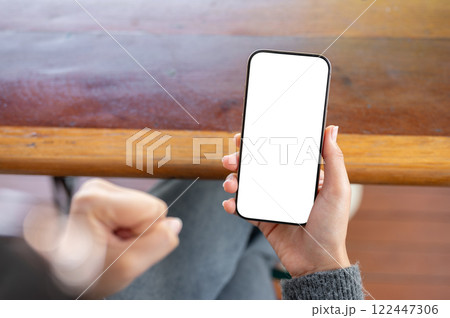 A woman holding a phone and clenching her fist in anger as she reacts to a video she is watching. 122447306