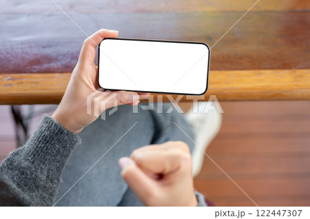 A woman holding a phone and clenching her fist in excite as she reacts to a video she is watching. 122447307