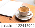 Open Blank Book and Cappuccino on Wooden Table in Cozy Cafe 122448094