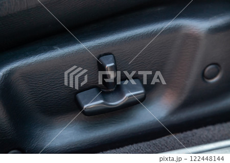 Buttons for adjusting the seat horizontally in height by tilting backrest with black leather upholstery in the car after cleaning and detailing in the vehicle repair workshop. Auto service industry. 122448144