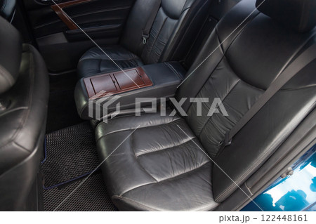 Clean after washing the rear passenger seats of matte black genuine leather inside the interior of an expensive SUV, preparation before selling the car. 122448161
