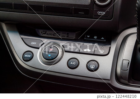 Close-up of the center console on a gray panel inside the car, with climate control and a red emergency button. Setting up and refueling the air conditioner in the workshop. Close-up of the center console on a gray panel inside the car, with climate control and a red emergency button. Setting up and refueling the air conditioner in the workshop. 122448210