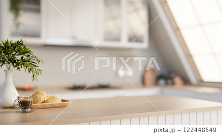 A minimalist hardwood kitchen tabletop adorned with decorative items, set in a sleek white kitchen. A minimalist hardwood kitchen tabletop adorned with decorative items, set in a sleek white kitchen. 122448549