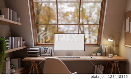 A cozy, minimal woody home office workspace features a computer on a desk, providing soft lighting. A cozy, minimal woody home office workspace features a computer on a desk, providing soft lighting. 122448556