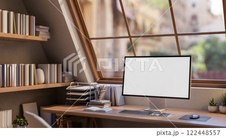 A computer on a hardwood desk by the window, with a bookshelf in a cozy Scandinavian-style apartment 122448557