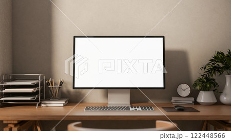 A front view of a computer and decorative plants on a hardwood desk against the wall in a cozy room. 122448566