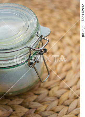 Glass jar with metal clasp on woven mat, rustic kitchen storage container. High quality photo 122448942