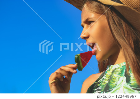 A little girl in a hat in summer. Teenage eating lollipop in shape of a watermelon. Sweets for children. A child with a candy. Childhood, summer vacation concept Female 10-12 years kid portrait A little girl in a hat in summer. Teenage eating lollipop in shape of a watermelon. Sweets for children. A child with a candy. Childhood, summer vacation concept Female 10-12 years kid portrait 122449967