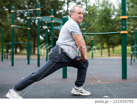 Elderly man doing gymnastics on an outdoor sports ground Elderly man doing gymnastics on an outdoor sports ground 122450795