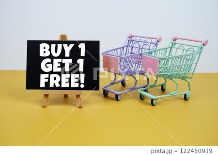 Buy 1 Get 1 Free text message and trolley shopping cart on yellow background Buy 1 Get 1 Free text message and trolley shopping cart on yellow background 122450919