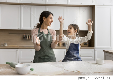 Candid laughing young mom little daughter play when rolling dough Candid laughing young mom little daughter play when rolling dough 122451274
