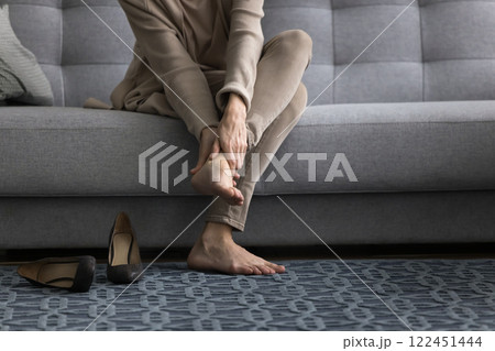 Middle aged woman sit on couch barefoot massaging fatigue feet 122451444