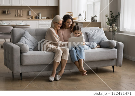 Grandma watching movie on notebook with grown daughter small grandchild Grandma watching movie on notebook with grown daughter small grandchild 122451471