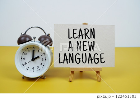 Learn A New Language text on paper card with alarm clock on yellow background 122451503
