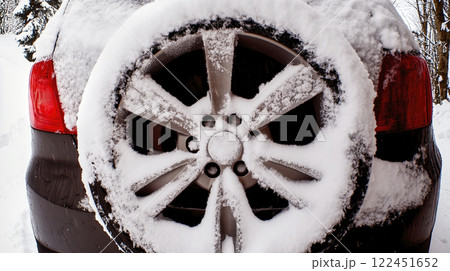 Snow covering spare wheel mounted on back of car in winter 122451652