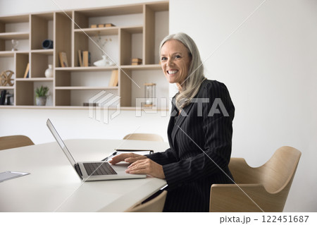 Joyful businesswoman sit at workplace with laptop in modern boardroom 122451687