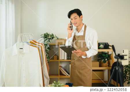 Young man business owner communicating with client and checking inventory on digital tablet 122452058
