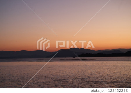 朝焼けの空とうつる海面の海と島の見える風景 122452258