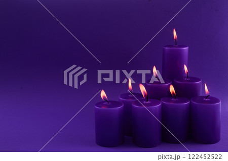 Beautiful burning violet candles on violet background Beautiful burning violet candles on violet background 122452522