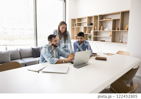 In modern conference room teammates engaged in workflow using laptop 122452805