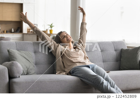 Mature woman stretch arms sitting on couch with closed eyes Mature woman stretch arms sitting on couch with closed eyes 122452809