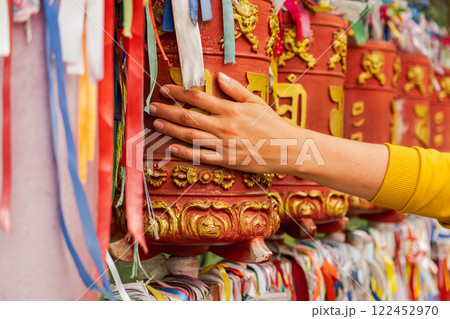 Person pilgrim female hand touching turning spinning Buddhist prayer wheel at Buddhist monastery. Prayer wheels in Buddhist stupa temple. Buddhism religion concept 122452970