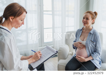 Female doctor examining pregnant woman in doctor office. Pregnant girl patient have consultation in hospital. Gynecologist doctor consulting patient about pregnancy. Visit to doctor medical checkup 122452979