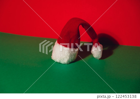 Santa hat on isometric green red background. Copy space for your text. Mock up for advertisement. Holiday Christmas composition. Minimalistic greeting card Santa hat on isometric green red background. Copy space for your text. Mock up for advertisement. Holiday Christmas composition. Minimalistic greeting card 122453138