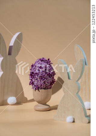 Creative Easter egg shape made of lilac spring petals flowers. Eco-friendly wooden bunnies decoration. Minimal holiday concept still life. Copy space greeting card 122453213