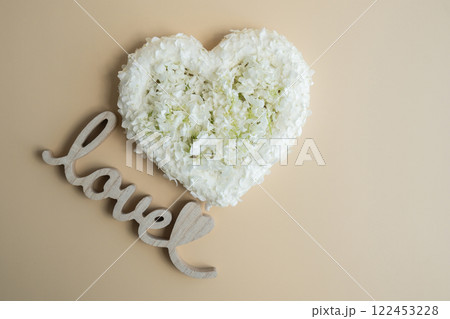 Wooden word LOVE White lilac flowers heart shaped in pastel backdrop. Symbol of love floral arrangement. Spring concept idea Valentine's Day, weeding proposal postcard copy space Wooden word LOVE White lilac flowers heart shaped in pastel backdrop. Symbol of love floral arrangement. Spring concept idea Valentine's Day, weeding proposal postcard copy space 122453228