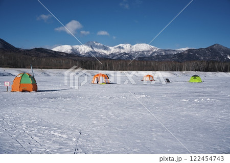 全面凍結した糠平湖のワカサギ釣りのテントから雪山を望む 全面凍結した糠平湖のワカサギ釣りのテントから雪山を望む 122454743