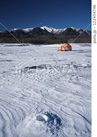 全面凍結した糠平湖のワカサギ釣りのテントから雪山を望む 122454746