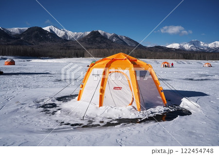 全面凍結した糠平湖のワカサギ釣りのテントから雪山を望む 122454748