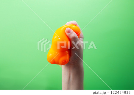 Hand squeeze orange stress ball on green background. Positive thinking concept Hand squeeze orange stress ball on green background. Positive thinking concept 122454935